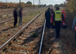 Пожилые люди пересекают железную дорогу, пробираясь под поездом, – одну из женщин сбило насмерть